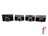 four cameras are lined up in a row on a white surface