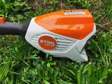 an orange and white stihl trimmer sitting in the grass