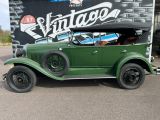 a green vintage car parked in front of a vintage sign