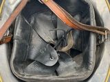 an old helmet with a leather strap on it sitting on top of a table