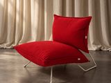 une chaise rouge sur laquelle est posé un coussin rouge, devant un rideau blanc