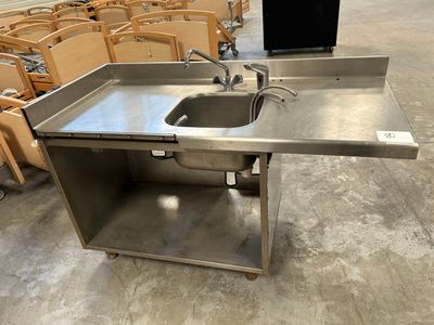 un évier en acier inoxydable dans une pièce où se trouvent des chaises vides