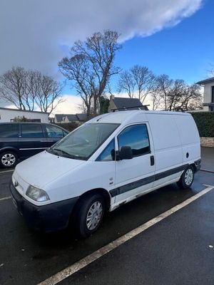la camionnette blanche est garée dans le parking à côté d'autres voitures