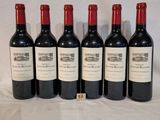 six bottles of red wine are lined up on a table