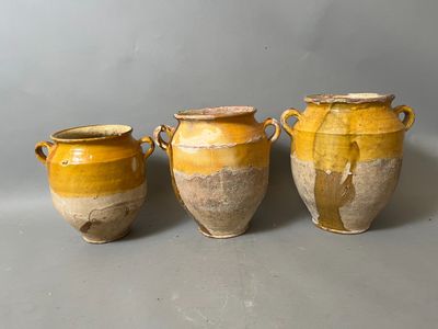 three yellow vases sitting next to each other on a gray surface