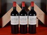 three bottles of red wine sitting on a table next to a wooden crate
