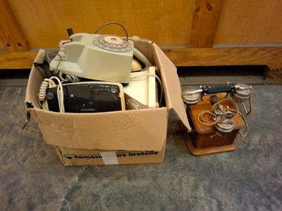 une boîte posée par terre, contenant un téléphone et d'autres objets