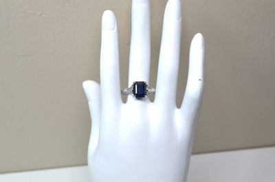 une main sur laquelle est passée une bague sertie d'une pierre bleue