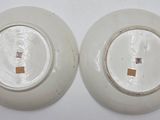 pair of white plates with gold rims on a white surface