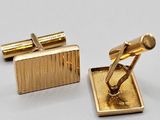 deux paires de boutons de manchette en or posés sur un fond blanc