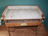a wooden table with a marble top and a drawer underneath it