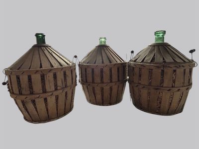 trois paniers marron sur lesquels sont posées des bouteilles vertes