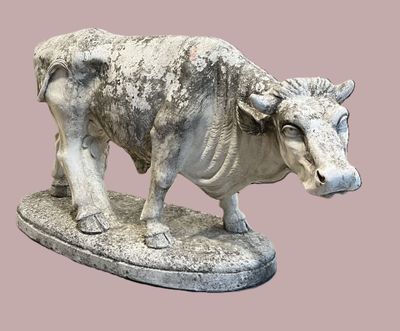 statue d'un taureau posée sur un socle en pierre, sur fond rose