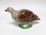 a ceramic bird sitting on top of a green object