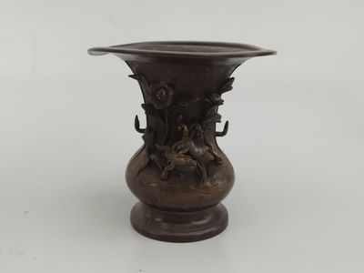 un vase en bronze posé sur une surface blanche