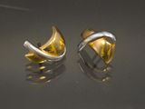 une paire de boucles d'oreilles en or et en argent posées sur un fond noir
