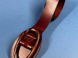brown leather belt with a metal buckle on a blue background