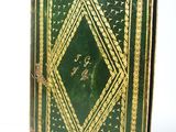 an old green book with gold trim and a diamond design on the cover
