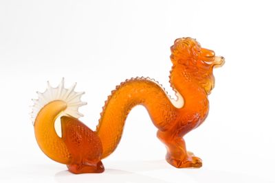 a glass figurine of a dragon on a white surface