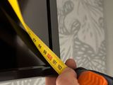 someone is measuring the height of a television screen with a yellow tape