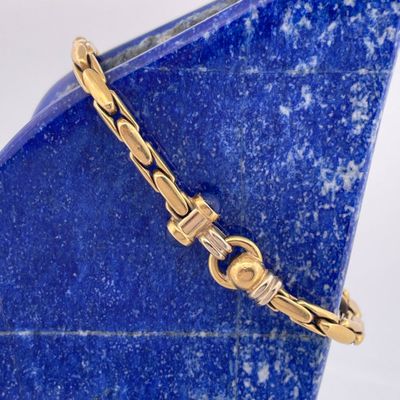 an image of a close up of a gold bracelet on a blue vase