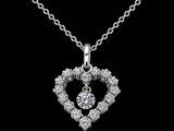 a diamond heart pendant on a silver chain on a black background