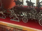 une vitrine contenant plusieurs figurines en bronze représentant des chevaux tirant une calèche