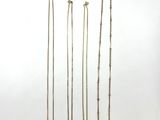 a group of four gold necklaces on a white background