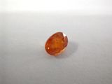 an orange sapphire stone sitting on top of a white surface