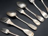 six silver spoons and a fork on a black surface