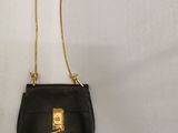 a small black purse with a gold chain hanging from it
