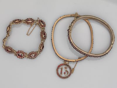 trois bracelets et un collier sont posés sur une surface blanche