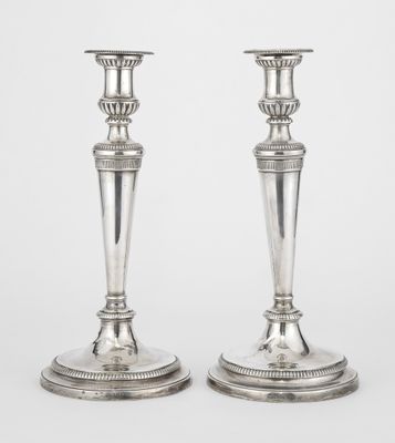 a pair of silver candlesticks on stands on a white background