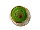 a green vase with a gold rim on a white surface