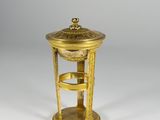 a gold plated clock with a stand on a white surface