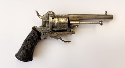 un revolver en argent avec une poignée en bois sur une surface blanche