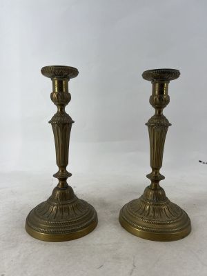 une paire de bougeoirs anciens en laiton posés sur une table en marbre