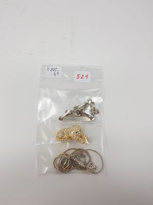 a close up of a bag of metal hooks on a white surface