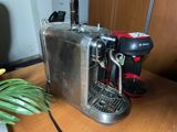 a silver toaster sitting on a table next to a green plant