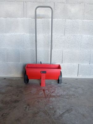 concrete floor with a red cart in it and a white wall in the background