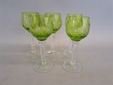 quatre verres à vin verts posés sur une surface blanche