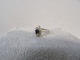 une photo d'une bague sertie d'un diamant et d'un saphir, posée sur un coussin