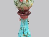 un vase surmonté d'une fleur, posé sur un socle
