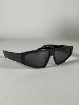 une paire de lunettes de soleil noires posée sur une surface blanche