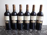 six bottles of wine are lined up in a row on a table