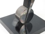a sculpture of a black object on a black base on a white surface