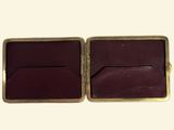 two pieces of brown leather with gold trims on a white surface