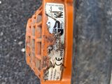 an orange chainsaw sitting on the side of a road next to a tire