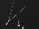 a black pearl and gold necklace and earring set on a black background