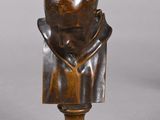 buste en bronze représentant un homme coiffé d'un chapeau, posé sur un socle en bois